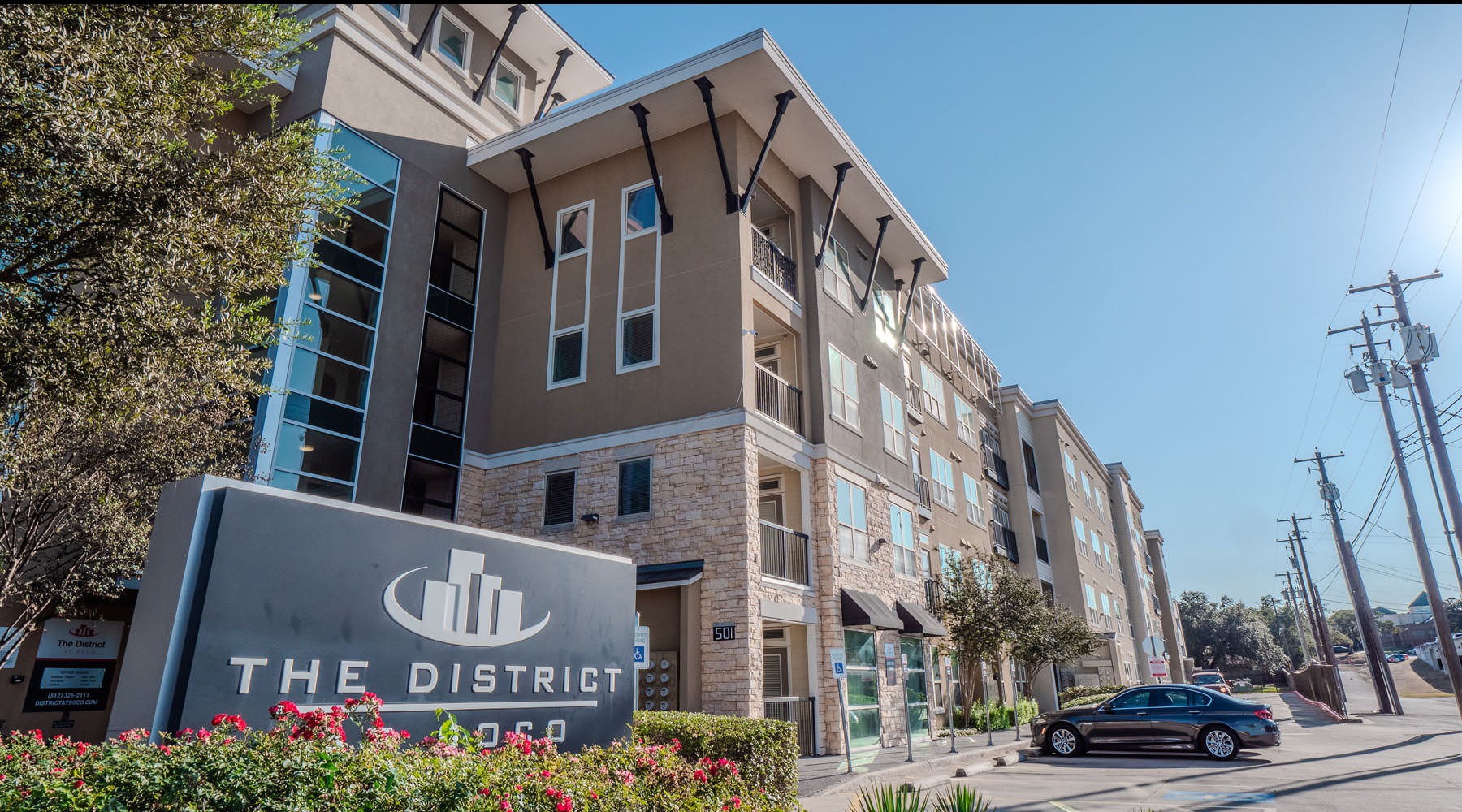 Find your perfect fit at District at SoCo a building with a sign in front and a car